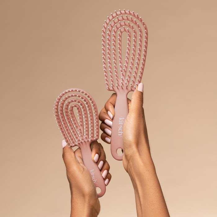 Hand holding the Kitsch Terracotta Detangling Flexi Brush Mini showing travel-friendly size