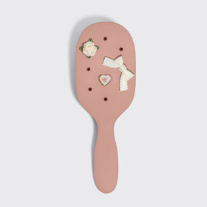 Pink hairbrush with decorative elements on a light gray background