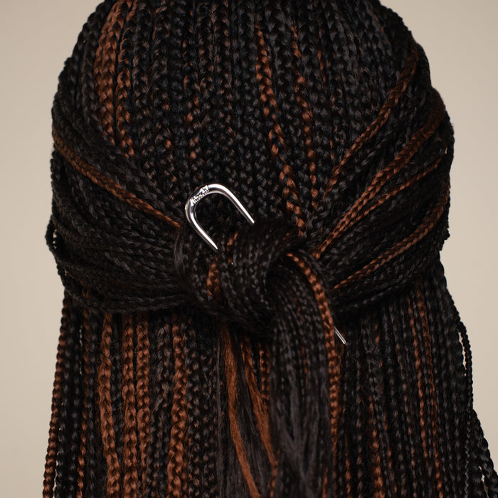 Close-up of braided hair with the kitsch silver mini metal french clip on a beige background