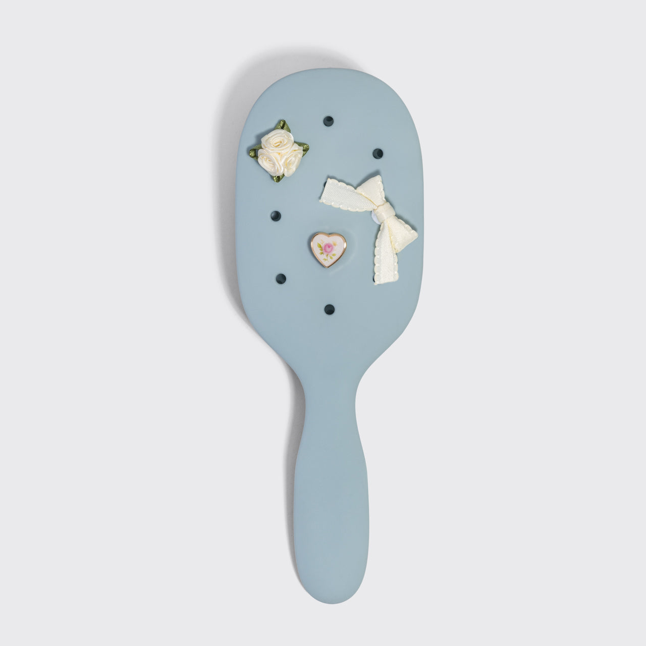 Decorative hairbrush with floral and bow designs on a light gray background