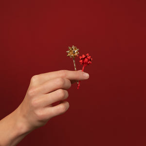KITSCH Red & Gold Metal Gift Bow Bobby Pins 4pc Set — hand holding one gold and one red bow pin against a deep red backdrop — Merry red and gold hues add a fun touch to any look — holiday celebrations