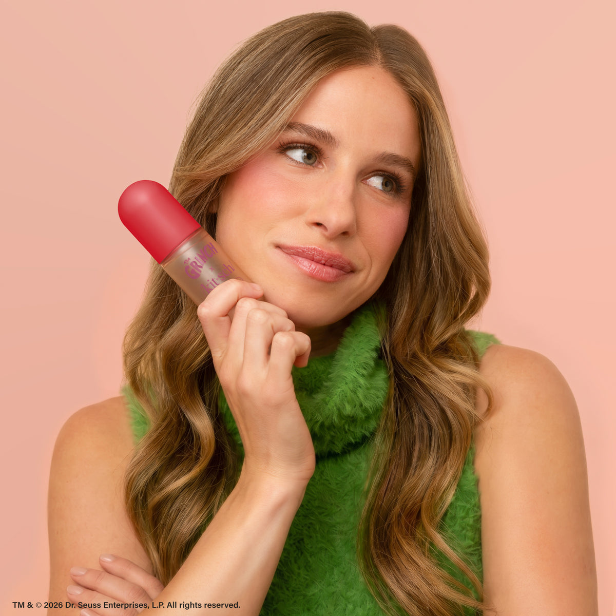Model holding The Grinch x Kitsch Cherry Cheer Hair Perfume bottle